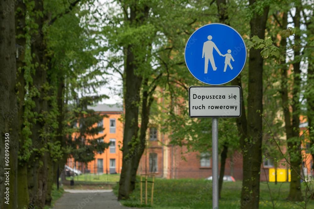 Blue circular shape road sign for pedestrians and cyclists in the city park. Caption below sign: Cycling is allowed. Blue circular shape road sign for pedestrians and cyclists in the city park. Caption below sign: Cycling is allowed.