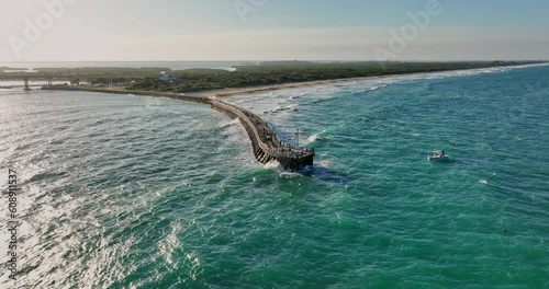 North Beach Florida Aerial v4 cinematic low level drone fly around Sebastian Inlet Fishing Pier capturing beautiful coastal scenery with waves crashing the shore - Shot with Mavic 3 Cine - March 2022