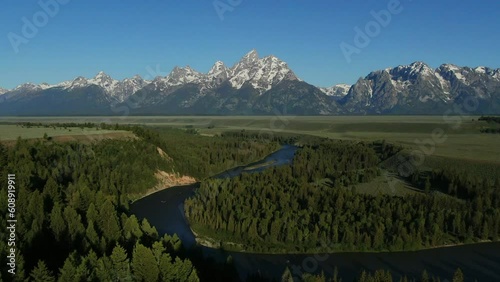 Aerial Cinematic Drone Jackson Hole Grand iconic Tetons Wyoming Snake River Spring greenery with snow capped mountain peaks vista point outlook turn out blue sky morning backward slowly movement photo