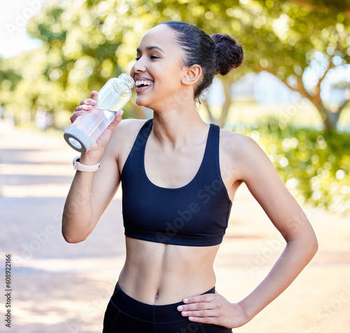 Happy woman, fitness and laughing with water bottle in rest from fun running, exercise or cardio workout in park. Fit, active or thirsty female person, athlete or runner with smile for sustainability