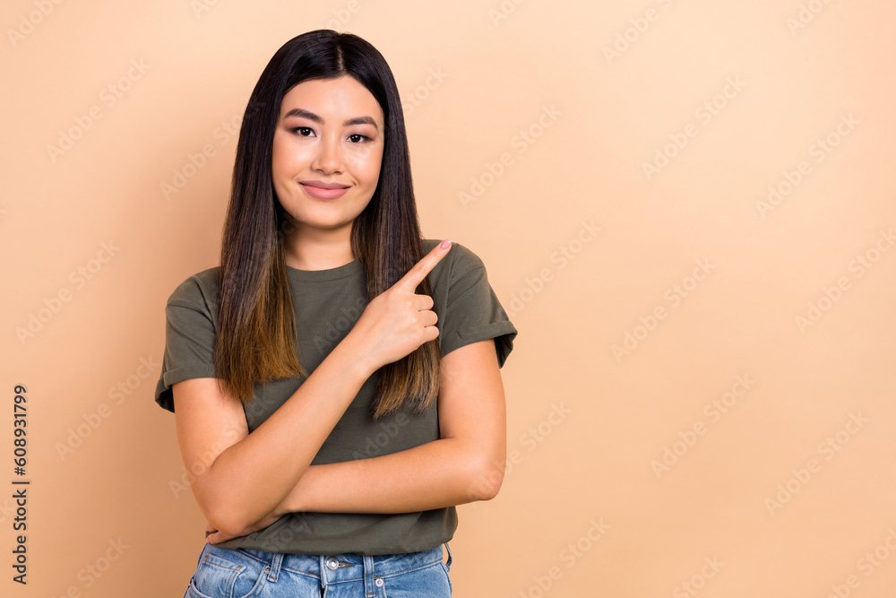 Photo of amazing beautiful asian girl direct finger empty space shopping banner wear stylish clothes isolated beige color background Photo of amazing beautiful asian girl direct finger empty space shopping banner wear stylish clothes isolated beige color background