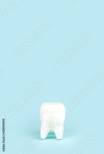 Ceramic model of tooth on blue background. Space for text.