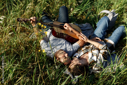 Happy couple in love on a romantic date at the park on a picnic. Playing on a guitar and having fun outdoors. Top view
