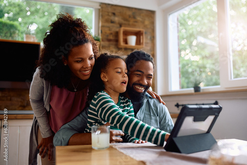 Happy black family using digital tablet together at home. photo