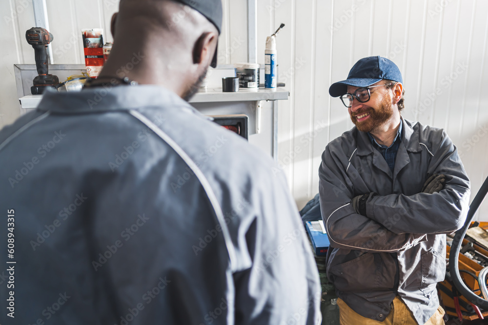 Two smiling men car mechanics during work break in repair service shop. High quality photo