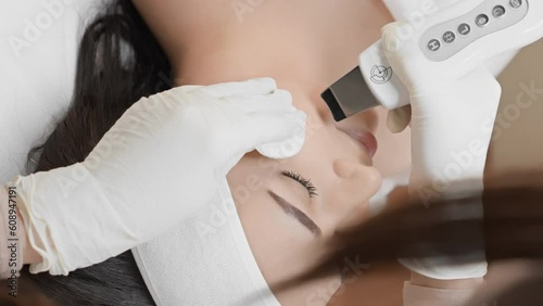 Intensive pore cleansing: watch how ultrasonic facial cleansing deeply cleanses skin pores, removing impurities and preventing blackheads and blackheads. Vertical video of the cosmetologist procedure photo