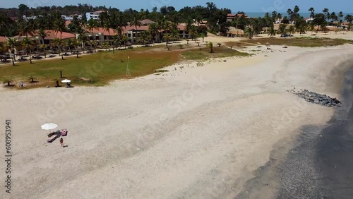 Aerial dolly shot over the beautiful Bakau beach overlooking the calm sea with waves, palm trees and a gorgeous hotel complex to travel photo