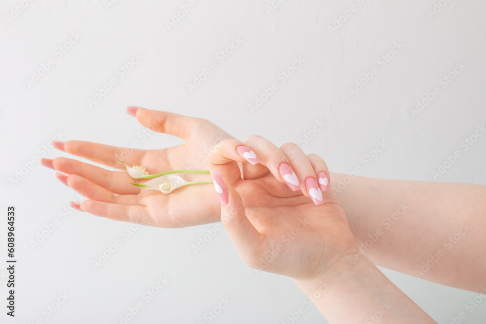 Fototapeta premium female hands with beautiful long nails with flowers on white background