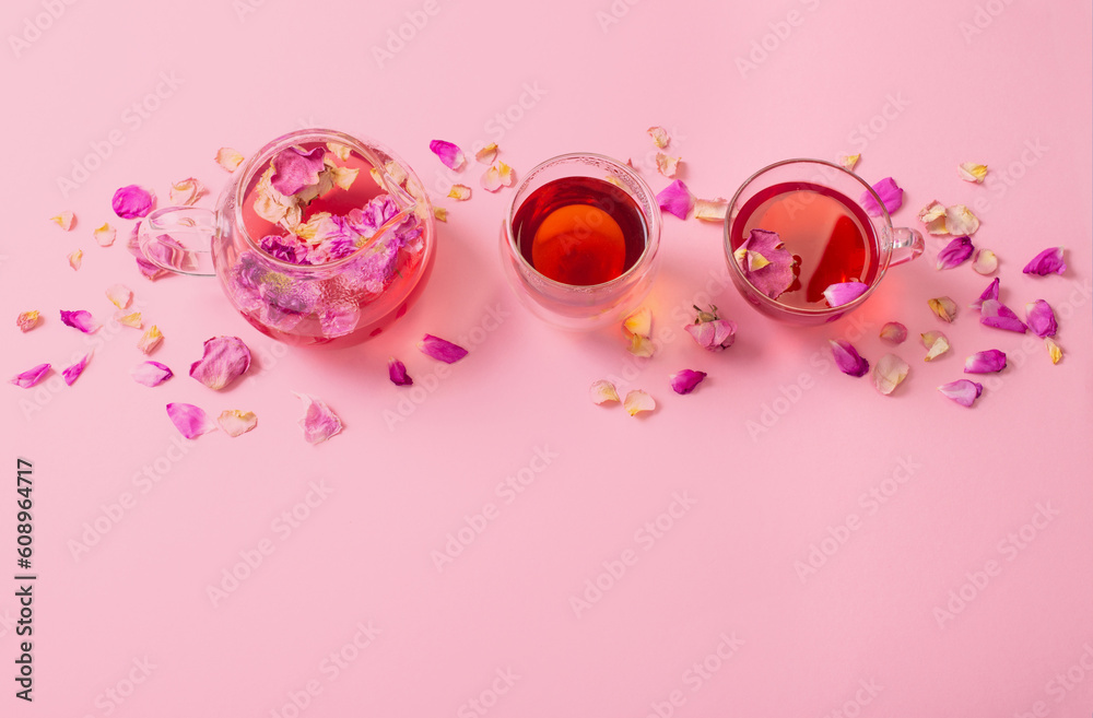 tea with rose petals in glass teapot on pink background