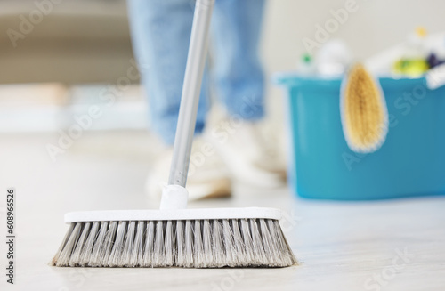 Cleaning, broom and sweeping with a maid in the living room of a home for housework or chores. Floor, sweep and housekeeper with a cleaner in a house to tidy for hygiene during a spring clean closeup photo