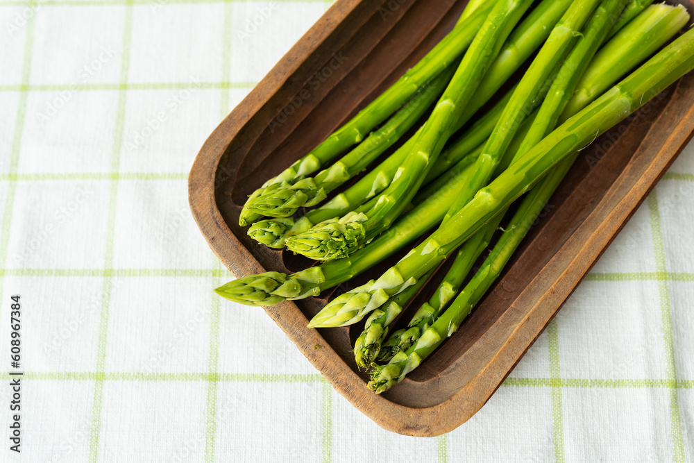 Green asparagus on a wooden plate. Clean and wholesome food for health. Vegetarianism, raw food. Healthy food concept. Green asparagus on a wooden plate. Clean and wholesome food for health. Vegetarianism, raw food. Healthy food concept.