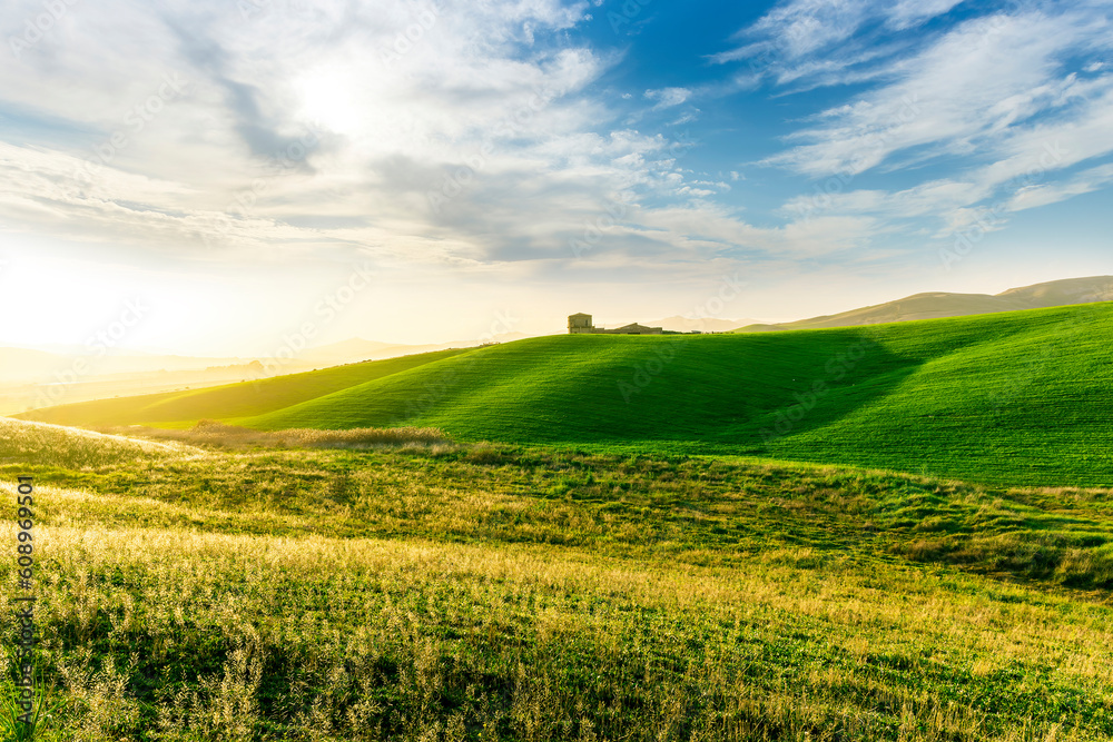 Fototapeta premium scenery rural view of a contryside farm in green fields and hills with amazing cloudy sky on background