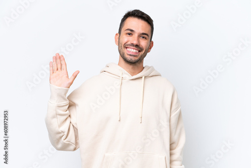 Young caucasian man isolated on white background saluting with hand with happy expression © luismolinero