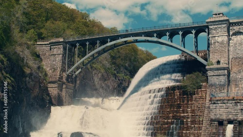 wide shot of bridge at the top of new croton dam with stepped spillway, trees and blue sky in the background. Slow motion 40fps. static. photo