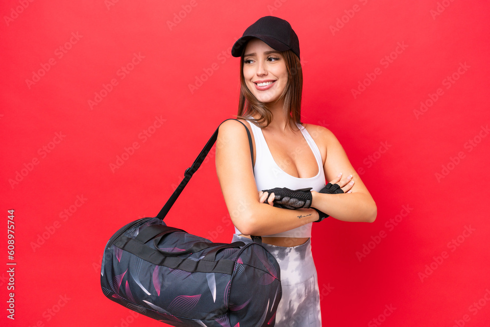 Young beautiful sport woman with sport bag isolated on red background with arms crossed and happy Young beautiful sport woman with sport bag isolated on red background with arms crossed and happy