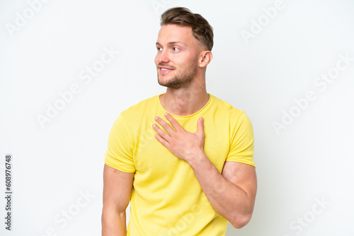 Young blonde caucasian man isolated on white background looking up while smiling