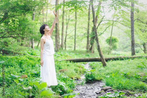 新緑の美しい森で森林浴をしている日本人女性/クリーンビューティーイメージ photo