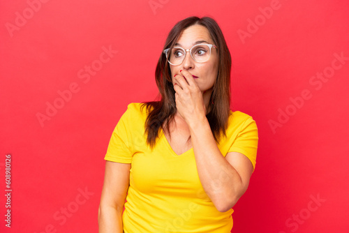 Middle-aged caucasian woman isolated on red background having doubts and with confuse face expression © luismolinero