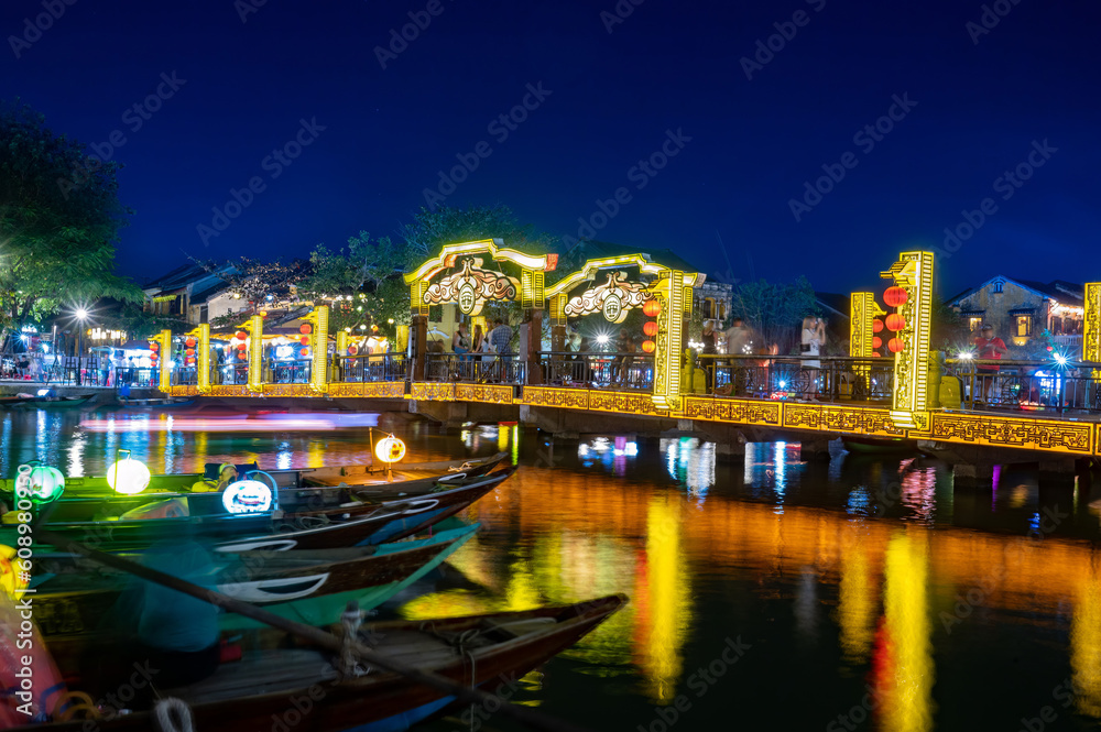 Multicolored illuminated bridge over river at night