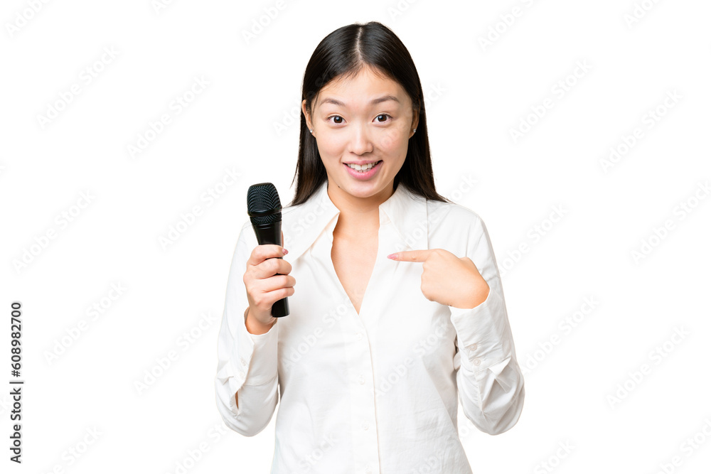 Singer picking up a microphone over isolated chroma key background with surprise facial expression
