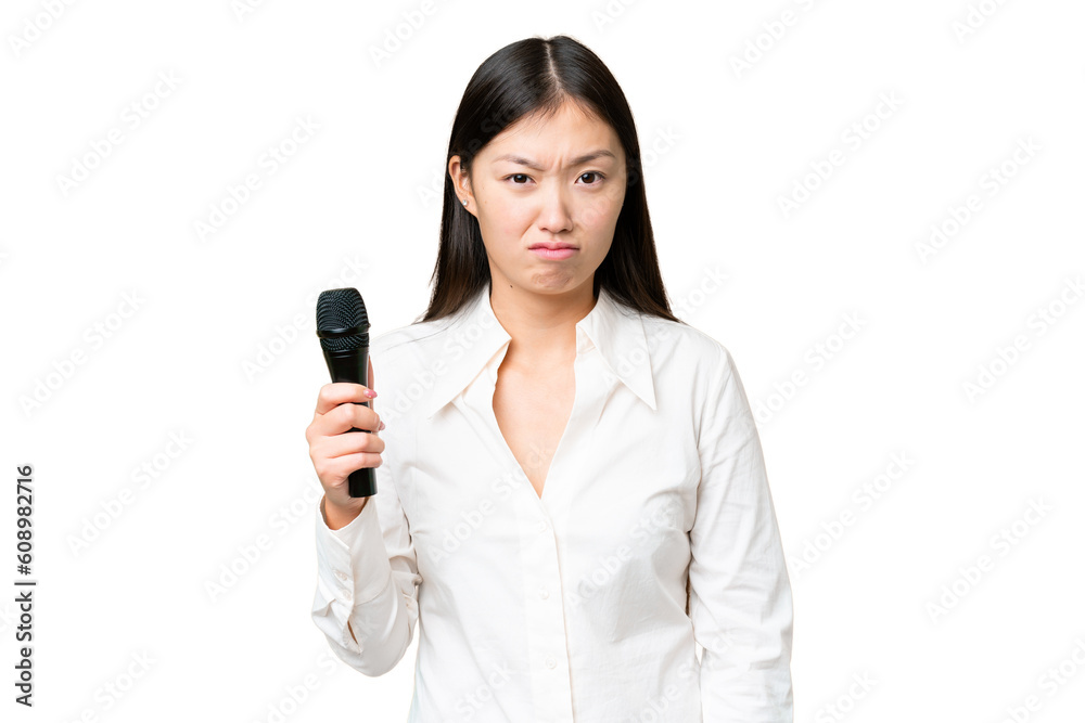 Singer picking up a microphone over isolated chroma key background with sad expression Singer picking up a microphone over isolated chroma key background with sad expression