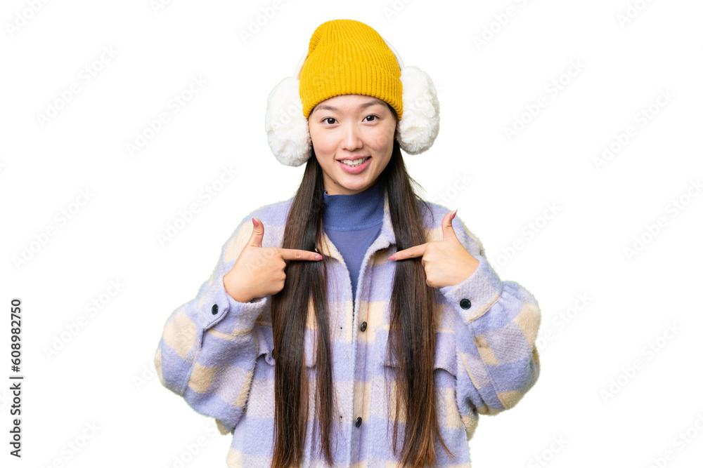 Young Asian woman wearing winter muffs over isolated chroma key background with surprise facial expression Young Asian woman wearing winter muffs over isolated chroma key background with surprise facial expression