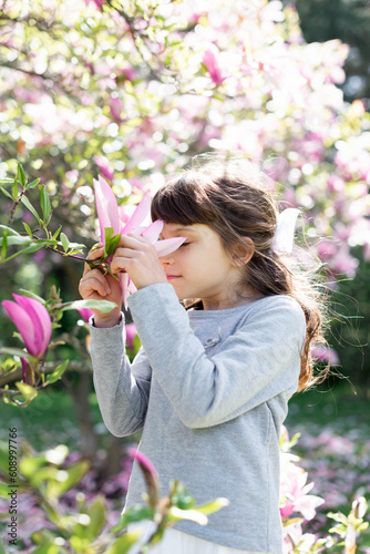 A cute girl inhales the aroma of pink magnolias photo
