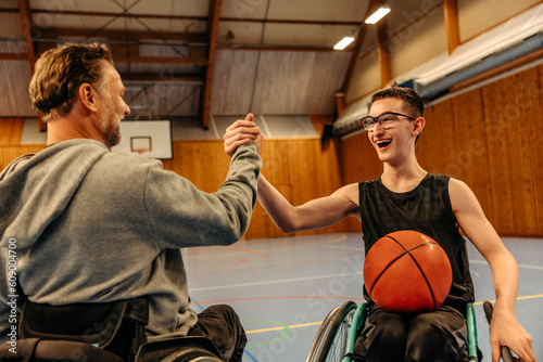 Cheerful male and female athletes with disabilities doing handshake while playing basketball at sports court photo