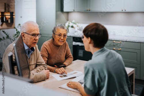 Senior couple discussing with interior designer over brochure while sitting at desk in store photo