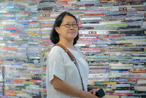 Asian woman standing in front of a wall made of books in an art exhibition photo