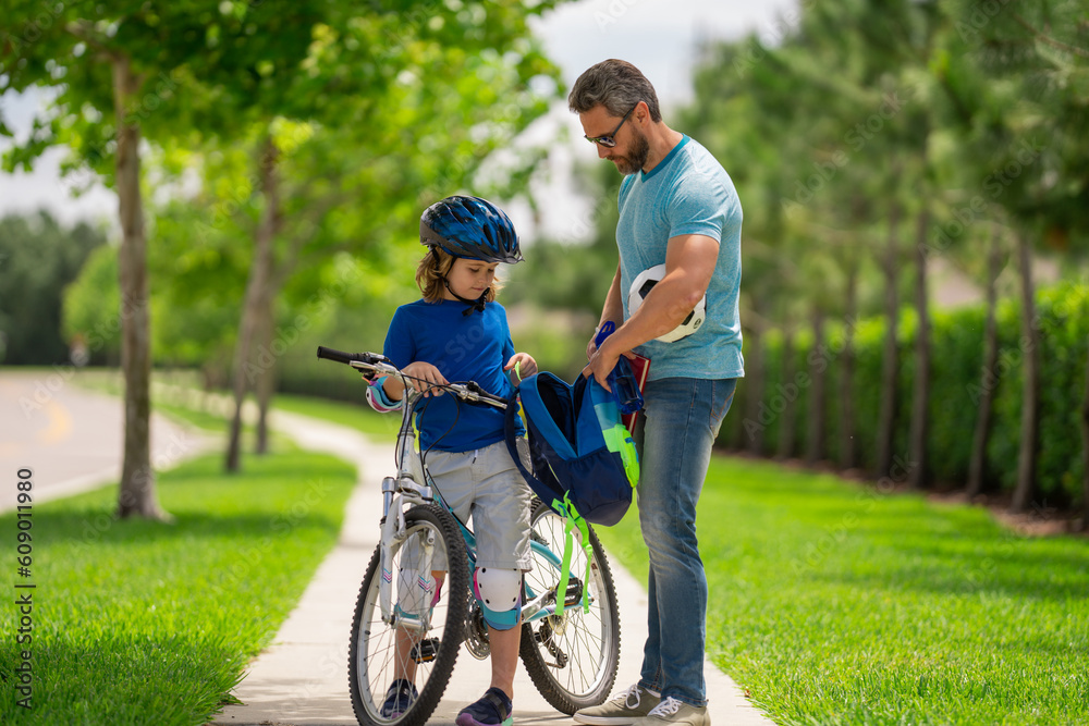 Father and son concept. Father teaching son riding bike. Father helping son to ride a bicycle in american neighborhood. Child in safety helmet learning to ride cycle with his dad. Fathers day. Father and son concept. Father teaching son riding bike. Father helping son to ride a bicycle in american neighborhood. Child in safety helmet learning to ride cycle with his dad. Fathers day.