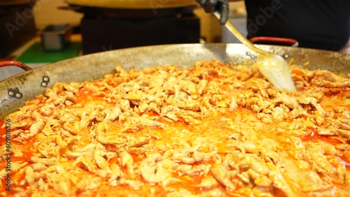 Stirring and cooking chicken stew in a commercial kitchen big metal container bowl