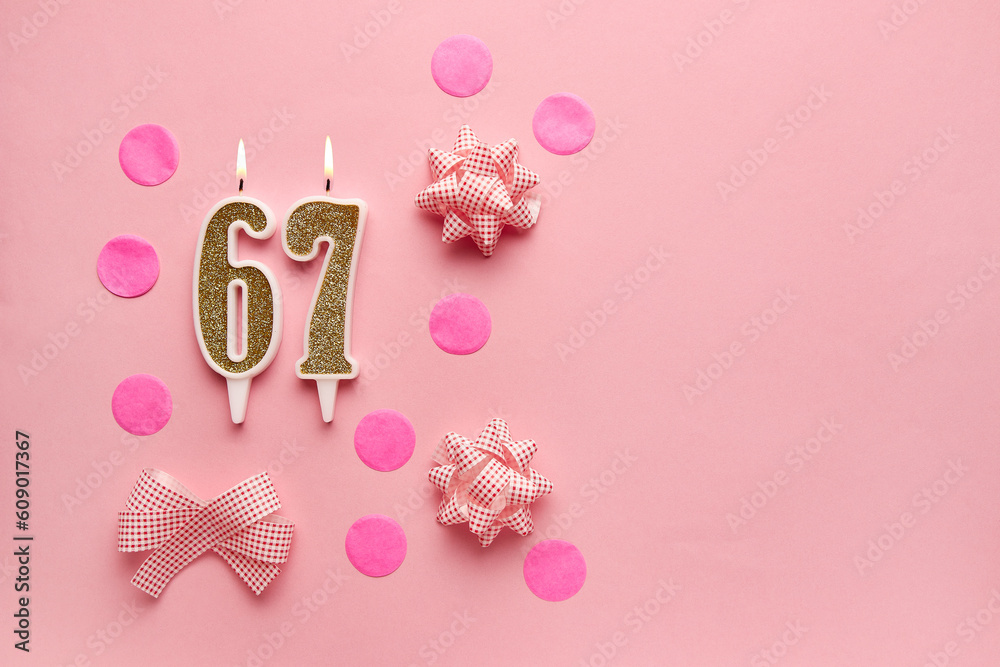 Number 67 on pastel pink background with festive decor. Happy birthday candles. The concept of celebrating a birthday, anniversary, important date, holiday. Copy space. banner