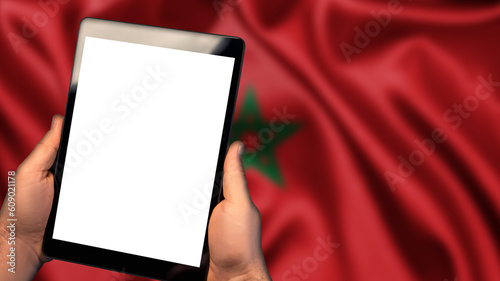 Man hold tablet phone pc gadget with white blank screen, copy space for text, image or message. Flag of Morocco country on background. Technology, information, business

