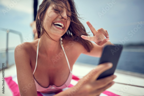 A young sexy girl is having a video chat on a smartphone while enjoying a sunbath. Summer, sea, vacation