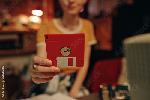 Young woman using floppy disk to save information from computer photo