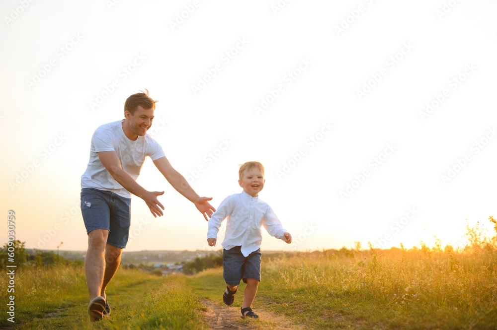 Father's day. Happy family father and toddler son playing and laughing on nature at sunset Father's day. Happy family father and toddler son playing and laughing on nature at sunset