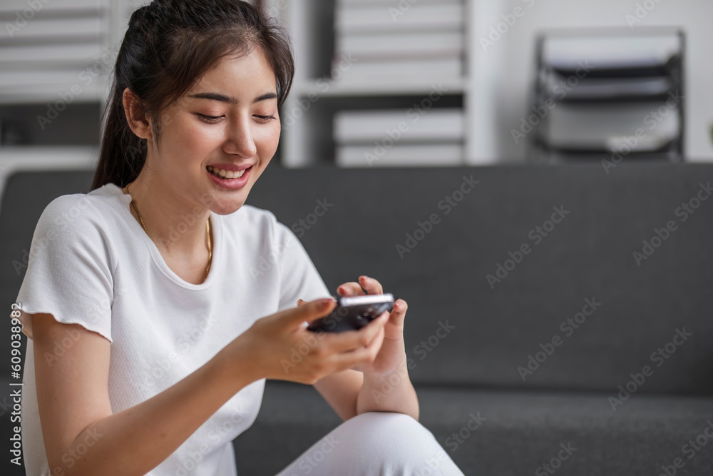 Shot of a happy young Asia woman taking selfie with her cellphone while sitting at living room. Shot of a happy young Asia woman taking selfie with her cellphone while sitting at living room.