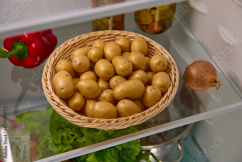 a basket of organic potatoes stands on a shelf in the refrigerator