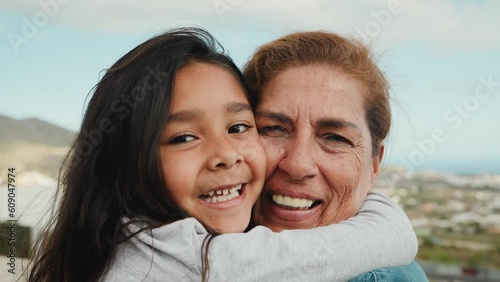 Happy Hispanic child enjoying time with grandmother smiling in front of camera at house rooftop