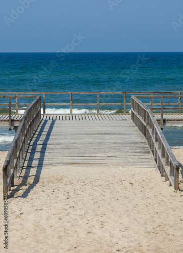 Wooden empty jetty or pier and beach by sea. Summer time © ratmaner