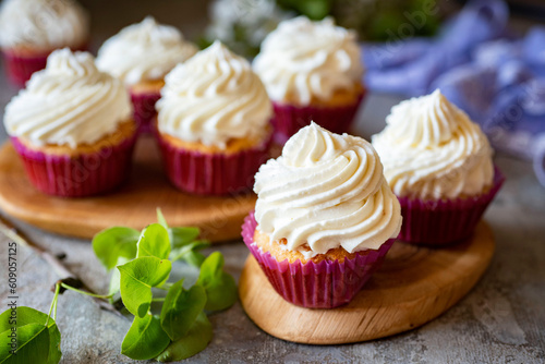 Sweet dessert: vanilla cupcakes with cream on a wooden stand. Close-up. Cake for breakfast