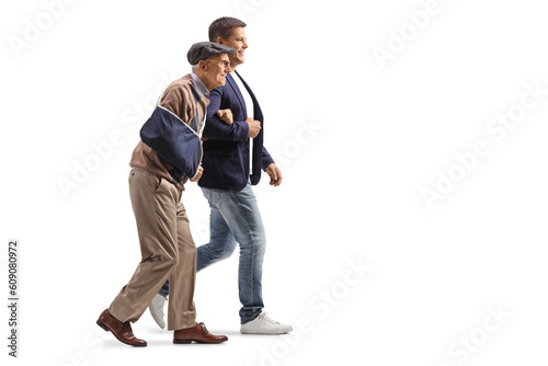 Young man walking with a senior man with an injured arm in a sling