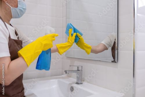 Woman cleaning mirrror with cloth and spray. photo