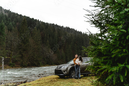 couple outdoors in the autumn season. lovers walk in a mountainous area near the river and forest. pastime of lovers during travel