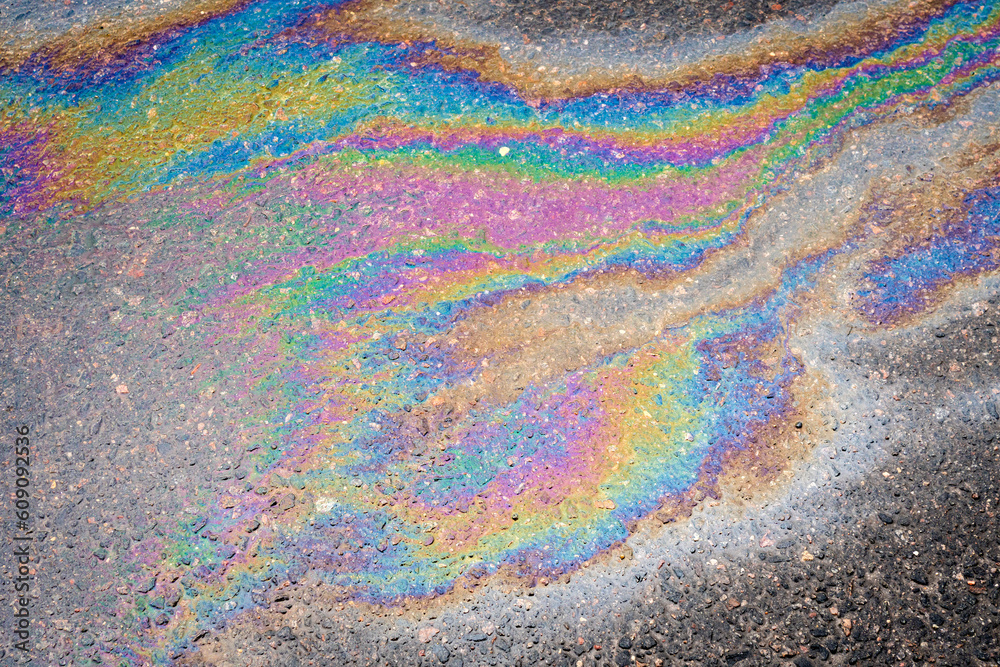 Petroleum fuel spilled on wet asphalt, abstract background