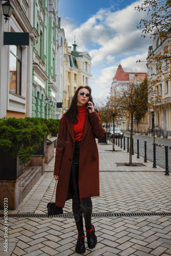 stylish Woman with a purse is walking down the street talking on her cell phone.