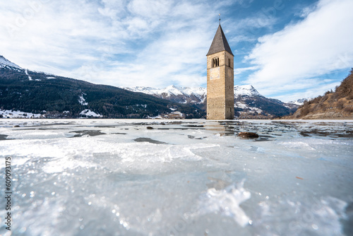 Winter scene at Resia Lake  with sunken gray steeple. Resia Lake is an artificial lake located in the western portion of South Tyrol, Italy, near the Resia Pass.