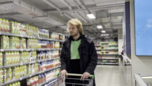 Wallpaper Mural Young man shopping in supermarket, reading product information. Torontodigital.ca