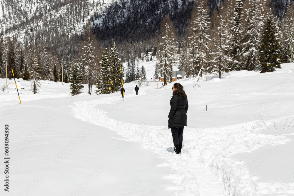 Woman walking on panoramic road on way up to Tre Cime di Lavaredo in a snowy winter day; Auronzo di Cadore; Belluno, Dolomites; Italy